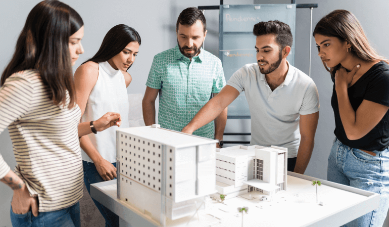 Cinco pessoas vendo uma maquete de imóvel