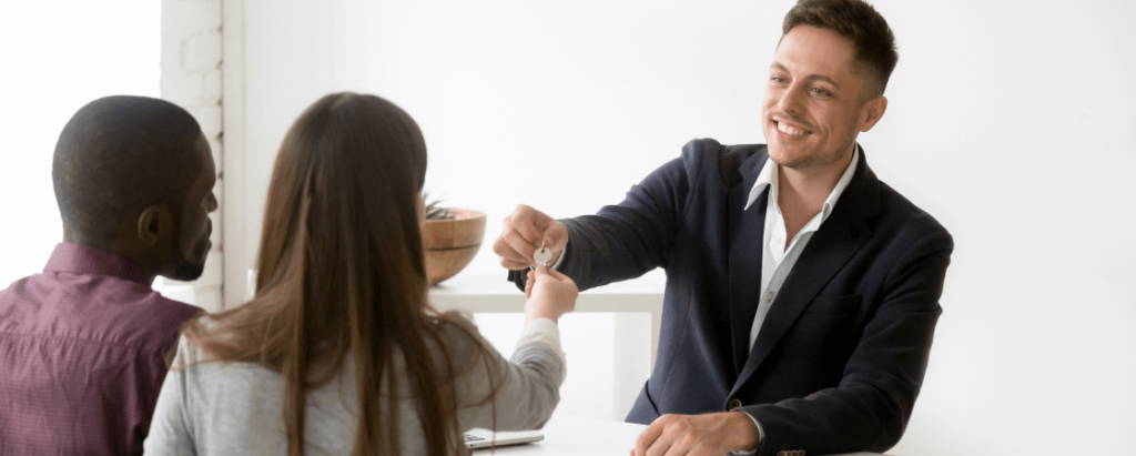 Homem entregando uma chave para um casal