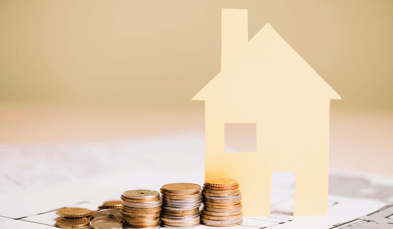 Moedas na frente de uma casa de papel